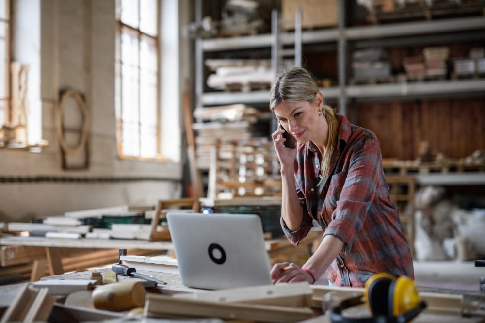 Tradie on computer talking to an insurance broker on the phone