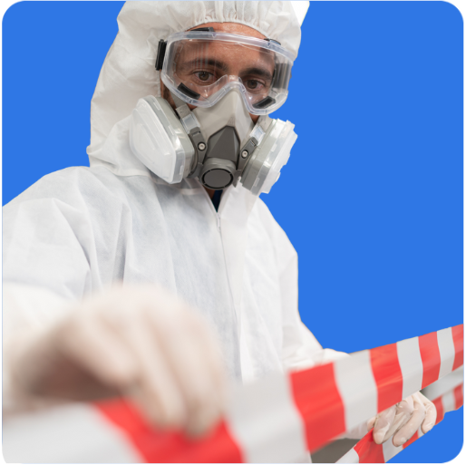 Person in protective gear, including a hazmat suit and respirator, holds a red and white striped barricade tape against a plain blue background, embodying the importance of asbestos liability insurance.