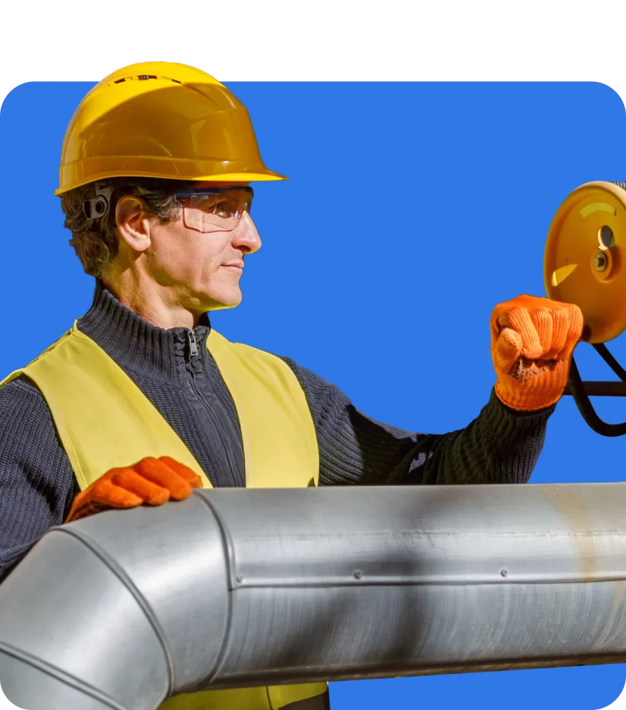 A worker in a yellow hard hat and safety vest operates a valve on a large metal pipe, wearing safety glasses and orange gloves, highlighting the importance of Contractual Liability Insurance. Blue background.