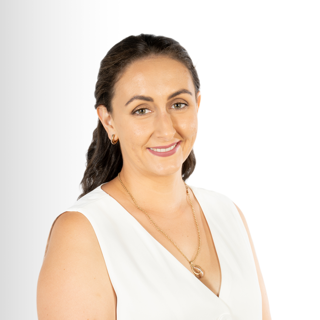 A woman with brown hair in a white sleeveless top, smiling and looking at the camera, against a white background.